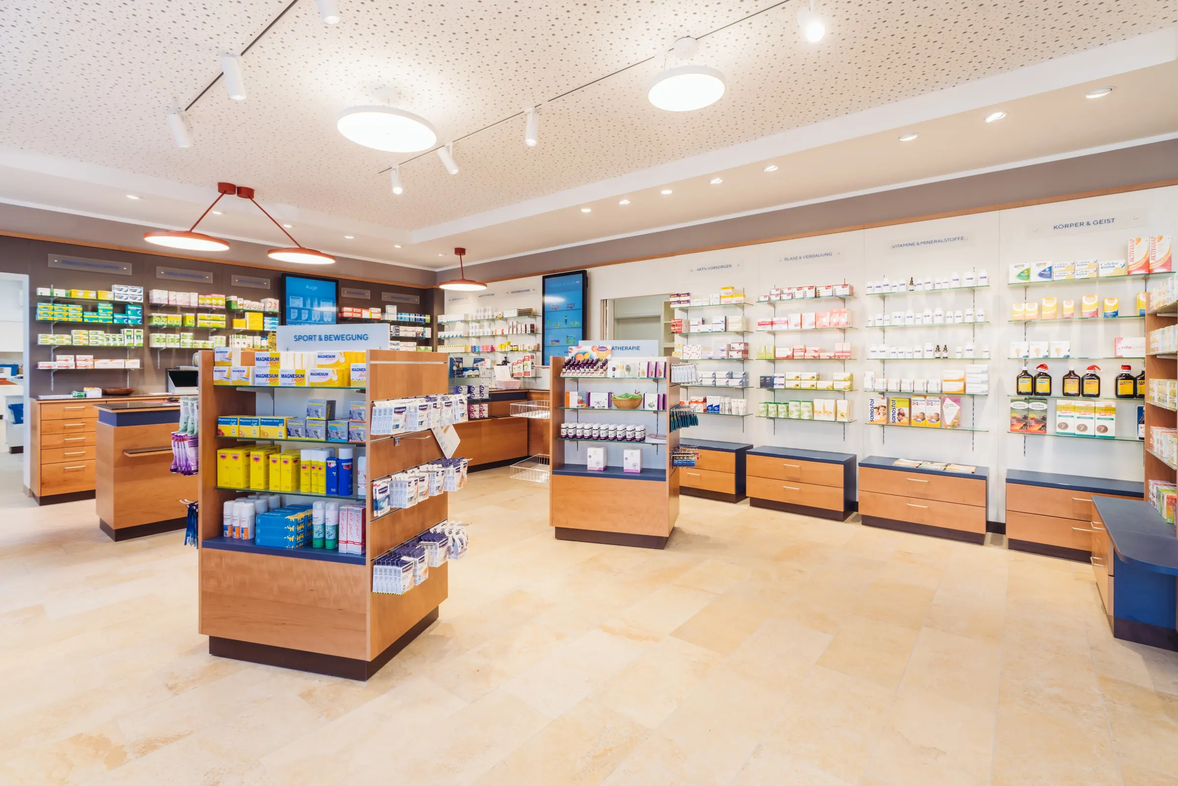 Heller Verkaufsraum der Christophorus Apotheke mit Holzregalen, Freiwahl-Inseln und Beratungstischen