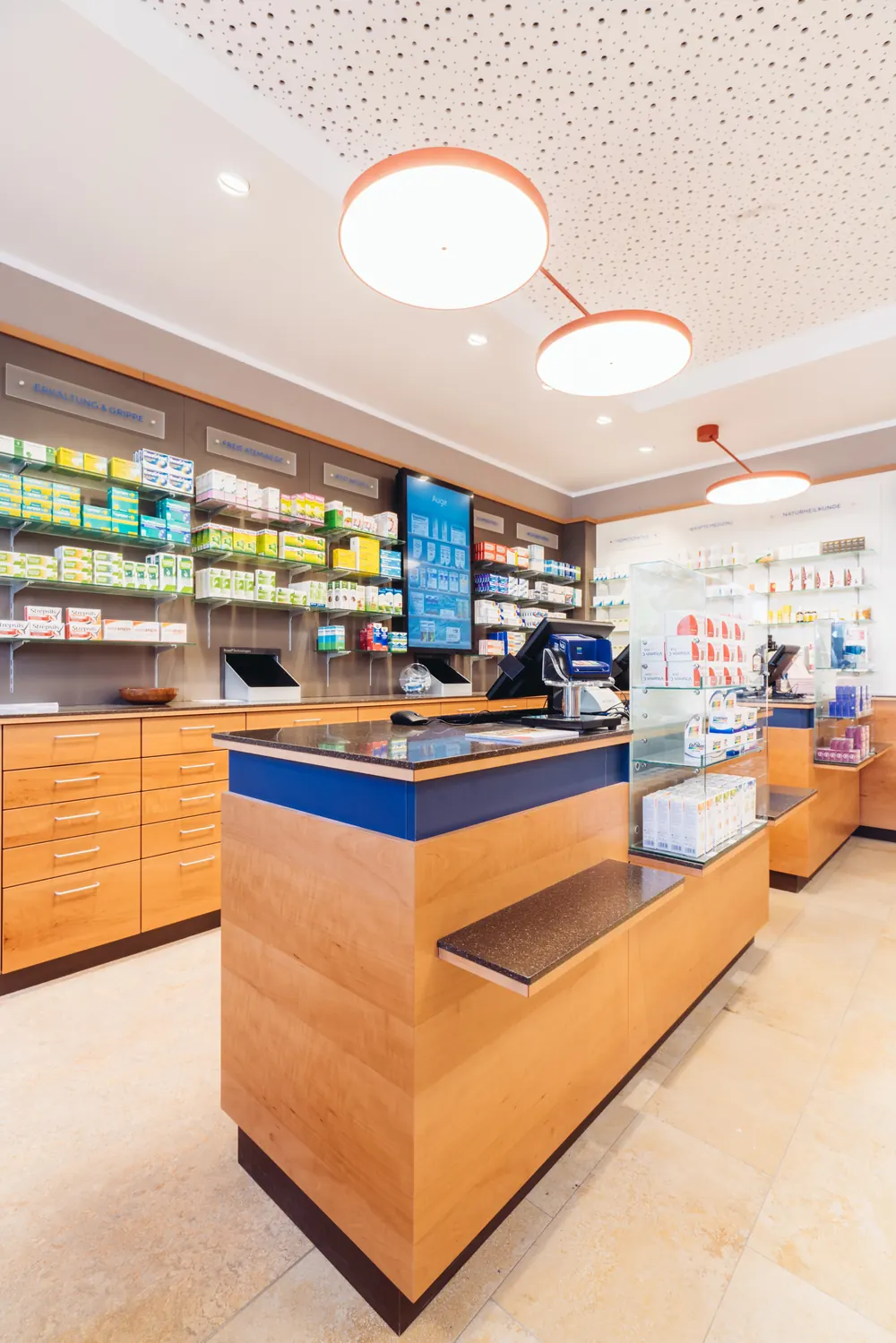 Beratungstisch aus Kirschholz mit blauer Kante in der Christophorus Apotheke, dahinter Regale mit Arzneimitteln